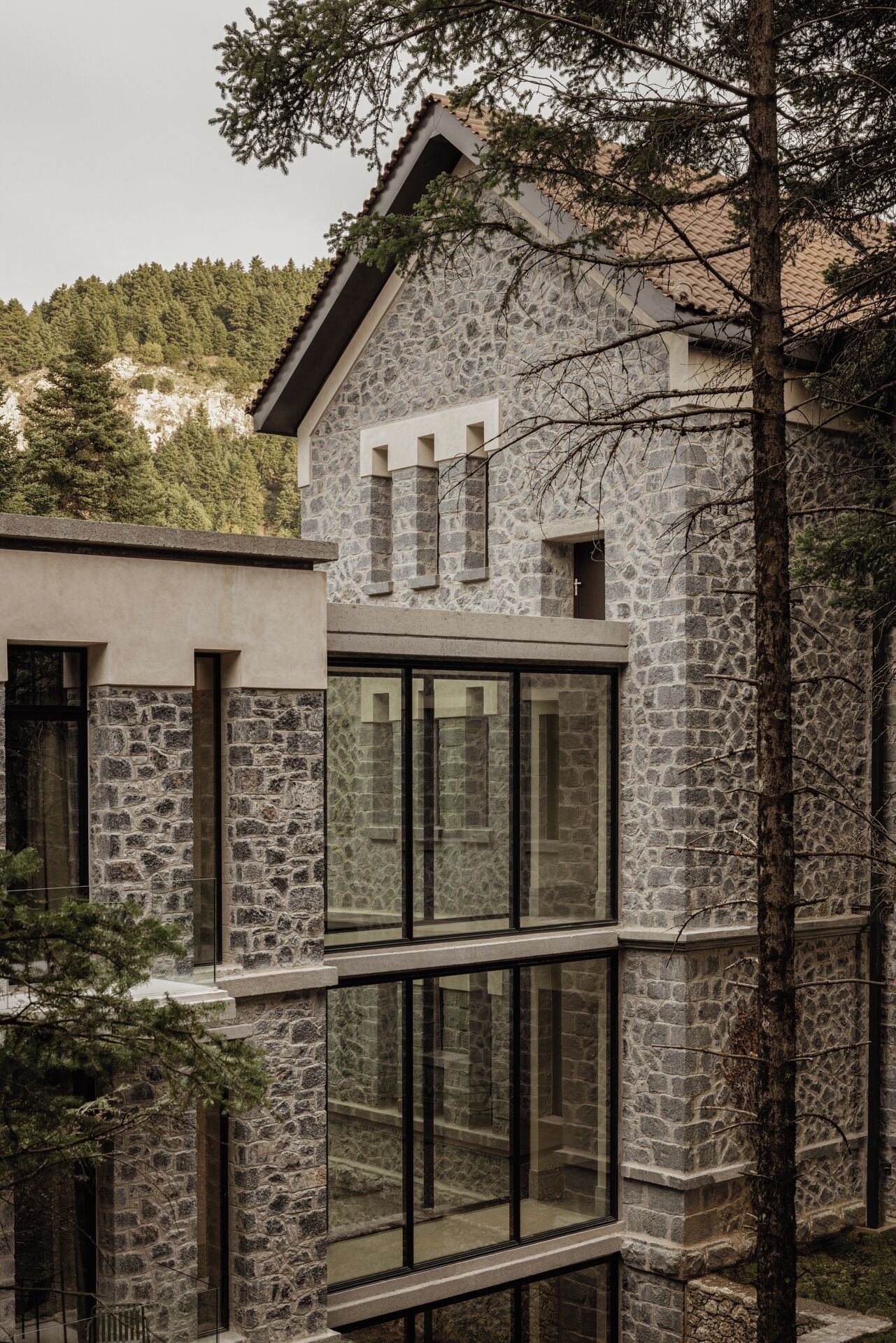 Un edificio in pietra con ampie finestre e un tetto spiovente.