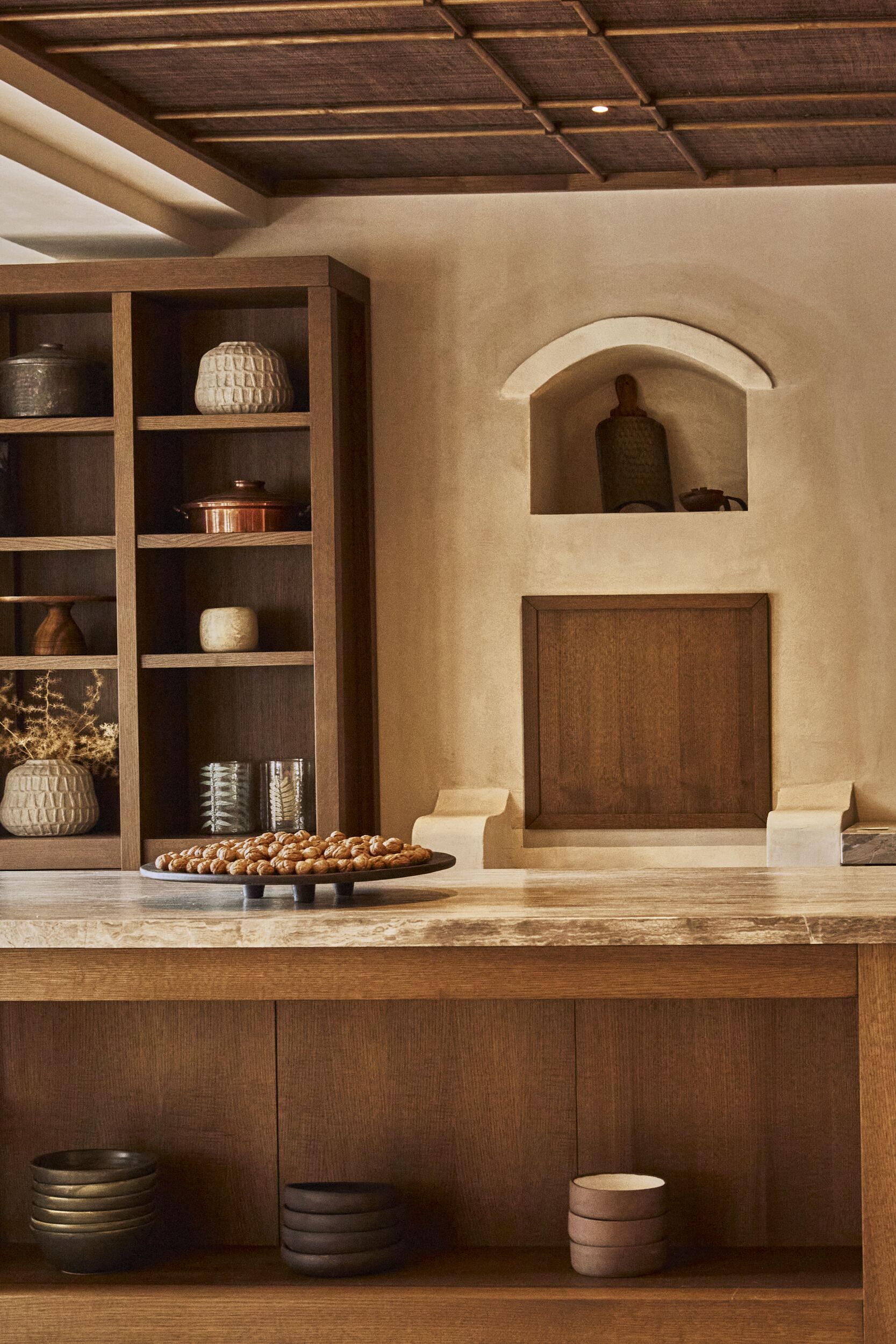 A kitchen with wooden shelves, a central island, and a built-in oven.