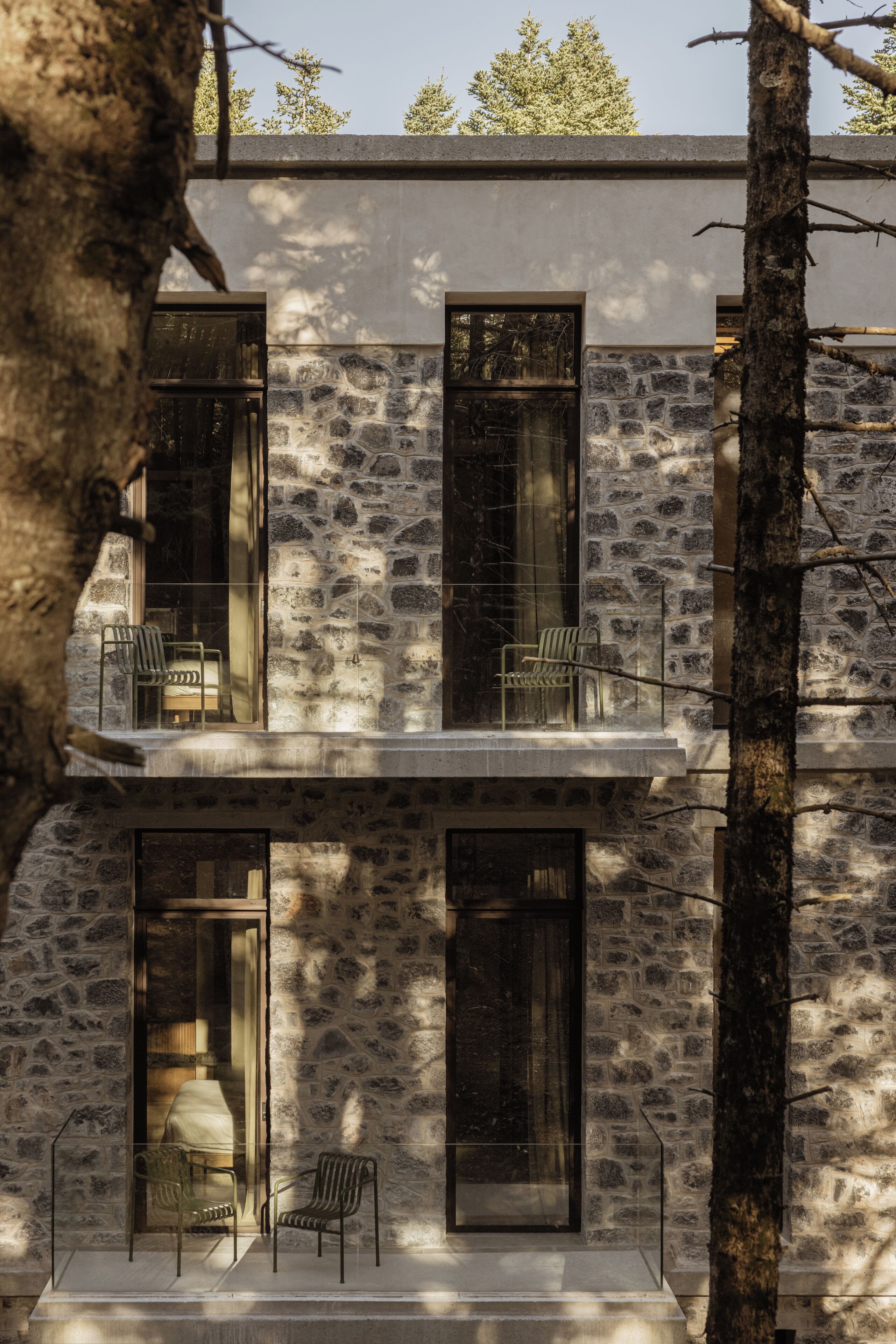Un edificio moderno con fachada de piedra, ventanas amplias y terraza.