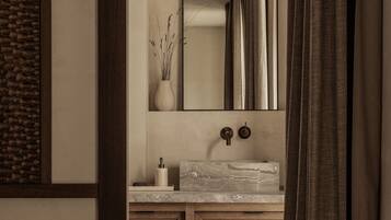 Un baño moderno con lavamanos de mármol, tocador de madera y un espejo grande.