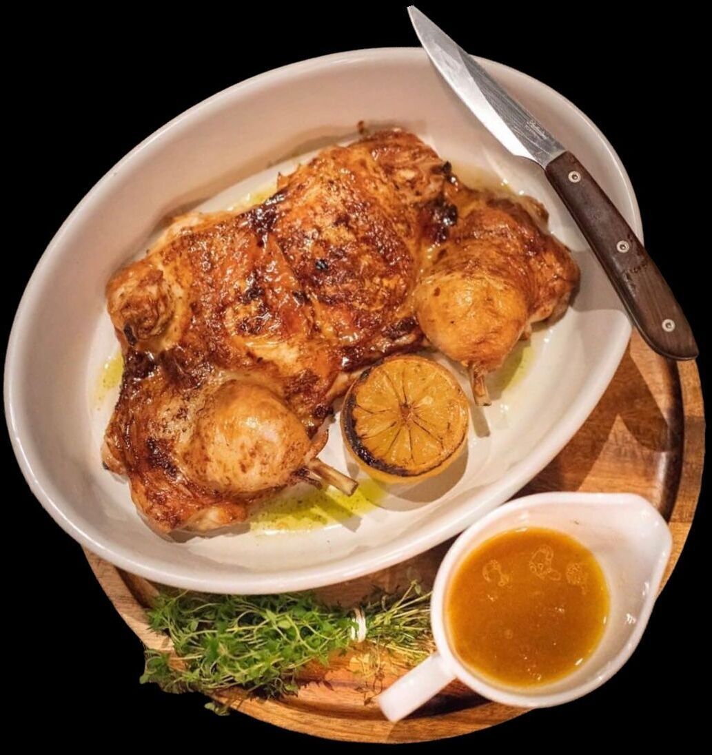 A roasted chicken with lemon and gravy on a plate.