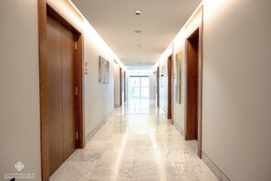 A hotel hallway with wooden doors, marble flooring, and recessed lighting. - Jasmine Garden Hotel (Jeddah)