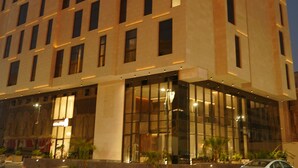 Un moderno edificio de hotel con varios pisos, grandes ventanales y un letrero llamativo.