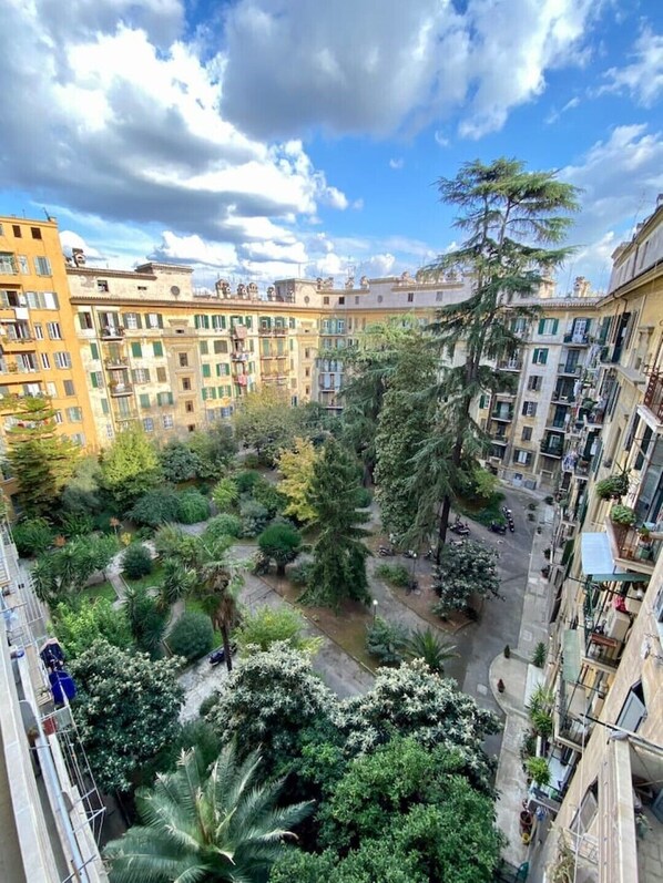 A courtyard with multiple buildings, trees, and a clear sky.