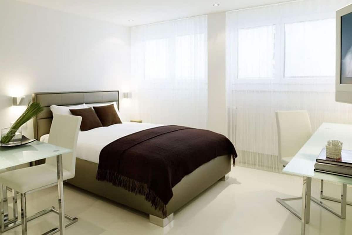 Une chambre d’hôtel moderne, dotée d’un grand lit, d’une table de chevet, d’une chaise et d’un bureau.