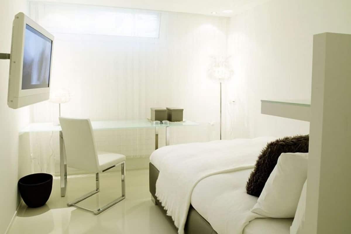 Une chambre d’hôtel moderne équipée d’un lit, d’un bureau, d’une chaise, d’une télévision et d’une salle de bain.
