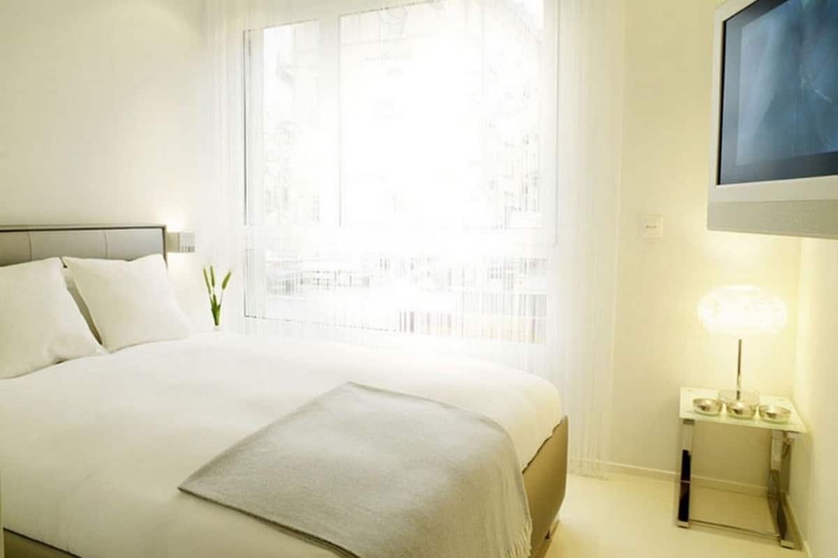 Une chambre d’hôtel bien aménagée, avec un grand lit, une table de chevet avec une lampe et un téléviseur fixé au mur.