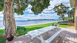 Eine Holzterrasse mit Picknicktisch und Stühlen mit Blick auf einen See und einer entfernten Insel.