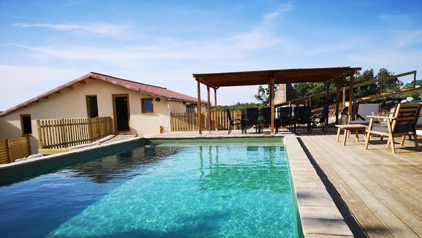 Ein rechteckiger Pool mit klarem Wasser, umgeben von einer Holzterrasse und einem überdachten Sitzbereich.