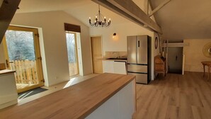 Eine geräumige Küche mit Holzarbeitsplatten, einem eingebauten Kühlschrank und einer Pendelleuchte.