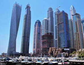 Ein Yachthafen mit zahlreichen Booten und einer Stadtansicht, die hohe Gebäude, darunter auch einige in Bau, zeigt.