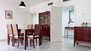 A dining area with a wooden table and chairs, a cabinet, and a mirror. - Spacious Poolside 3 Bedroom F-5 (Marbella)