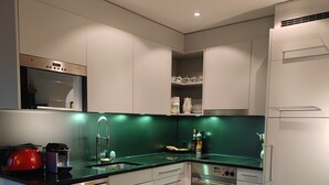 A modern kitchen with white cabinets, a black countertop, and a green backsplash.