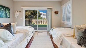 A bedroom with two beds, a large window, and a view of a house and garden. - Refined 3BR Retreat in the Heart of Inner Richmond, Near Presidio, Golden Gate Park & Clement Street (San Francisco)