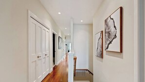 A hallway with wooden flooring, white doors, and artwork on the walls. - Refined 3BR Retreat in the Heart of Inner Richmond, Near Presidio, Golden Gate Park & Clement Street (San Francisco)