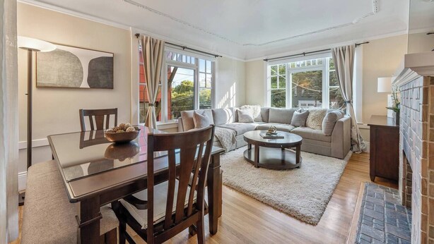 A spacious living room with a wooden dining table, a sofa set, and a fireplace. - Serene Inner Richmond 3BR Retreat Near Golden Gate Park, Clement Street & Geary Blvd (San Francisco)