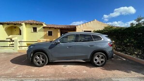 Un SUV gris était garé devant un bâtiment jaune dont le toit était recouvert de tuiles.