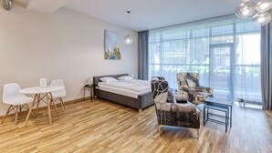 A modern hotel room with a large bed, a dining table with chairs, a sofa, and a small table. - Fresh and lovely apartment (Jurmala)