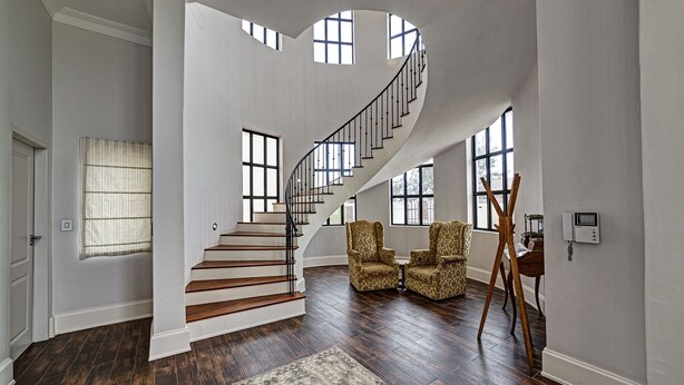 A spacious foyer with a curved staircase, large windows, and a wooden floor. - Lagoon Suites Boutique Hotel (Walvis Bay)