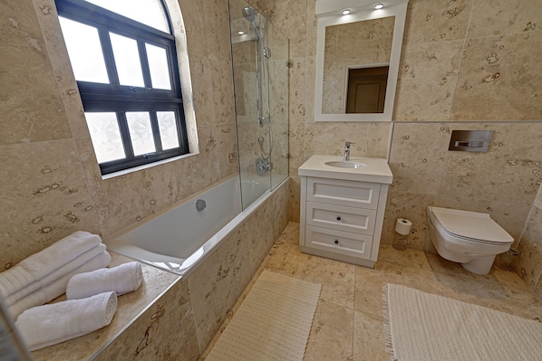 A bathroom with a bathtub, a sink, a toilet, and a window. - Lagoon Suites Boutique Hotel (Walvis Bay)
