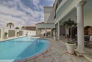 Una piscina al aire libre, sombrillas, sillones reclinables de piscina