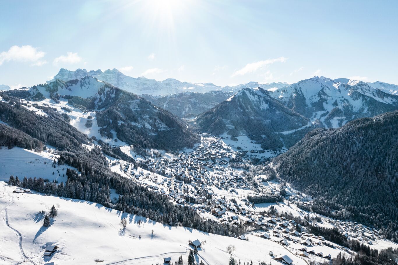 A snow-covered mountain village with a valley and distant peaks.