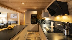 A modern kitchen with wooden ceiling beams, a central island, and a dining area with a sofa and table. - Apartment for 9 people at 500m from Linga gondola - Chatel Reservation (Châtel)