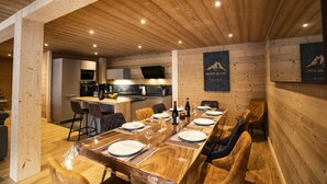 A wooden-paneled dining area with a long table set for six, a kitchen in the background, and a sign on the wall reading "MONT. BALANG". - Apartment for 9 people at 500m from Linga gondola - Chatel Reservation (Châtel)
