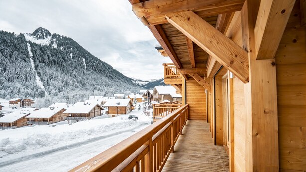 A wooden balcony with a view of snow-covered houses and a mountain in the background. - Apartment for 9 people at 500m from Linga gondola - Chatel Reservation (Châtel)