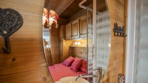 A compact wooden cabin interior with a bed, a sink, and cabinets.