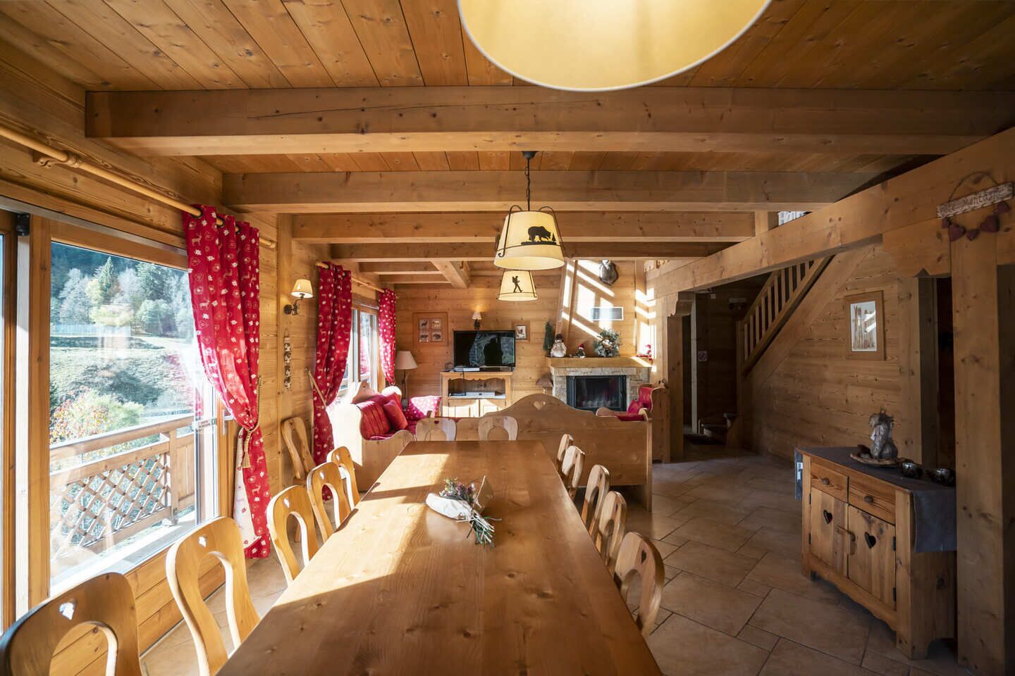 A wooden cabin with a dining area, kitchen, and a fireplace.