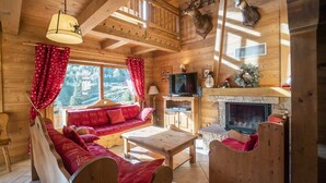 A cozy log cabin interior with a wooden sofa, a fireplace, and mounted animal heads.