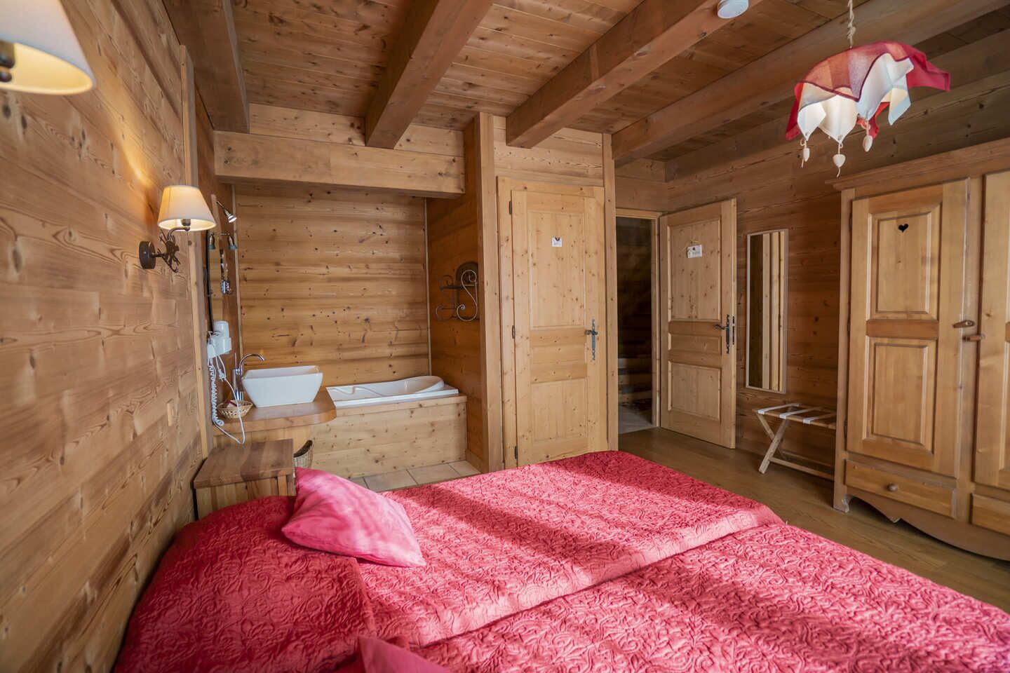 A wooden cabin room with a bed, a sink, and a shower.