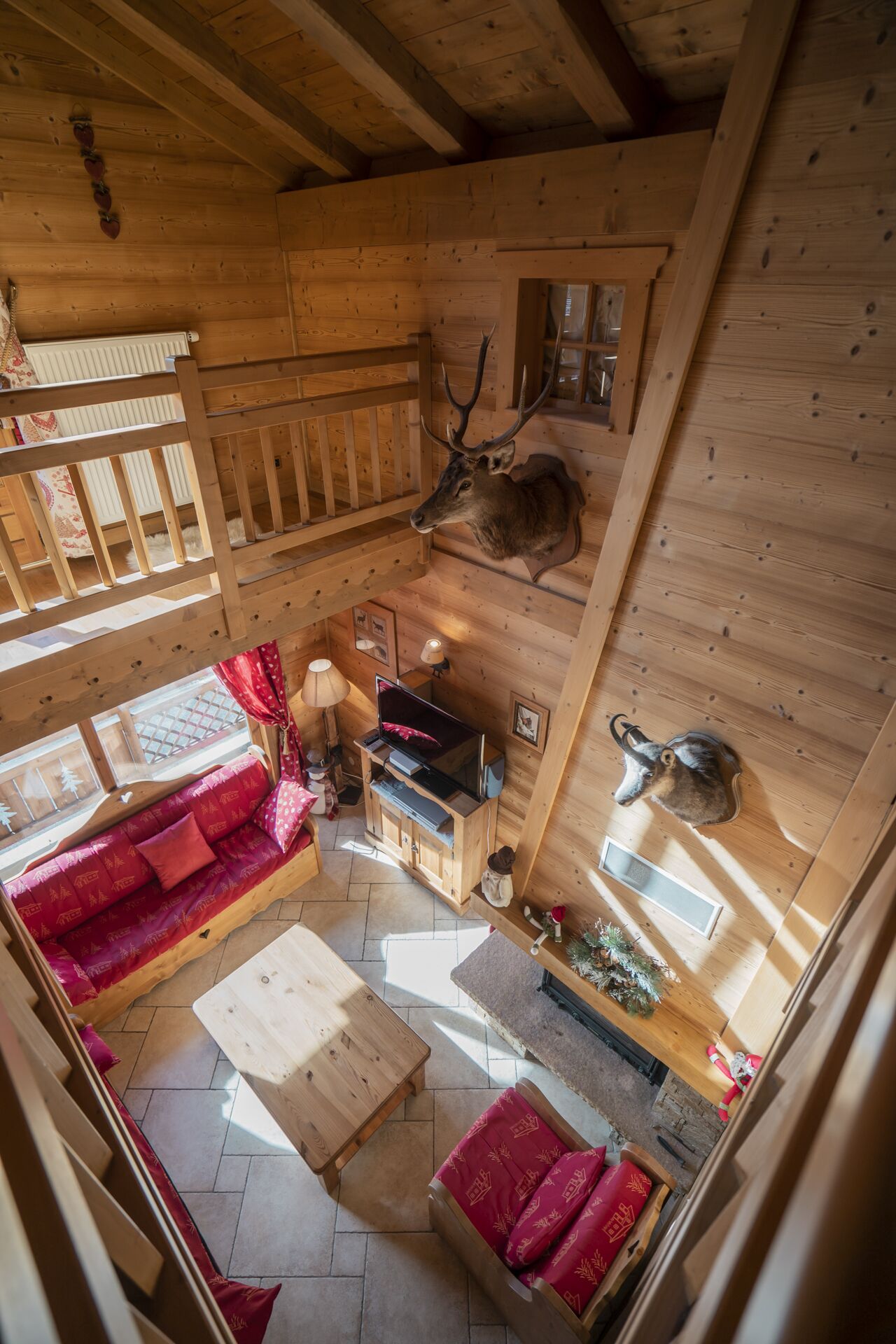 A cozy wooden cabin interior with a sofa, a television, and a mounted deer head.