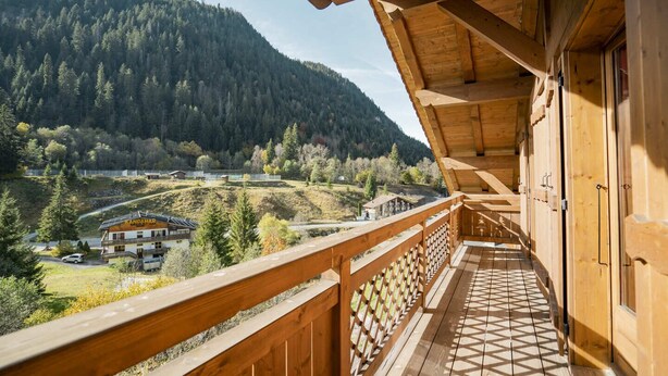A wooden balcony with a view of a mountainous landscape and a building labeled "RandaHof".