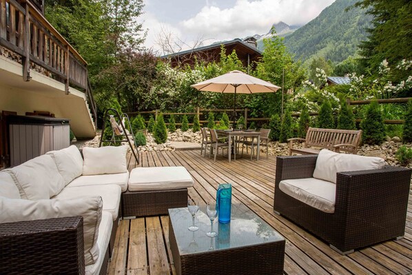 A wooden deck with outdoor furniture, including a sofa and chairs, and a table with a glass top.