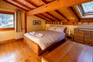 A wooden bedroom with a bed, bedside table, and a dresser.