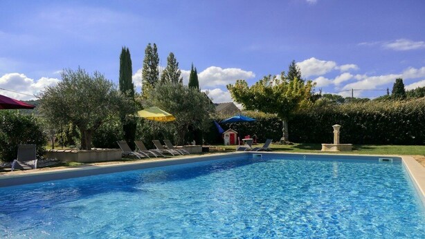 A clear swimming pool with lounge chairs and umbrellas, surrounded by trees and a small building. - Les Demeures de la BeauClaire - Provençal Elegance, Pool, Air Conditioning, Warm Hospitality (Piolenc)