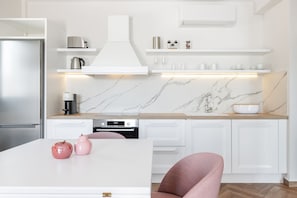 A modern kitchen with white cabinetry, a marble backsplash, and a stainless steel refrigerator.