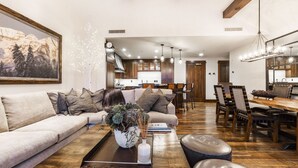 Un salón amplio con un sofá grande, una mesa de centro con una planta y un comedor con sillas y mesa de madera.