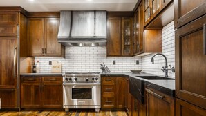 Una cocina con armarios de madera, estufa de acero inoxidable y un revoque de ladrillo blanco.