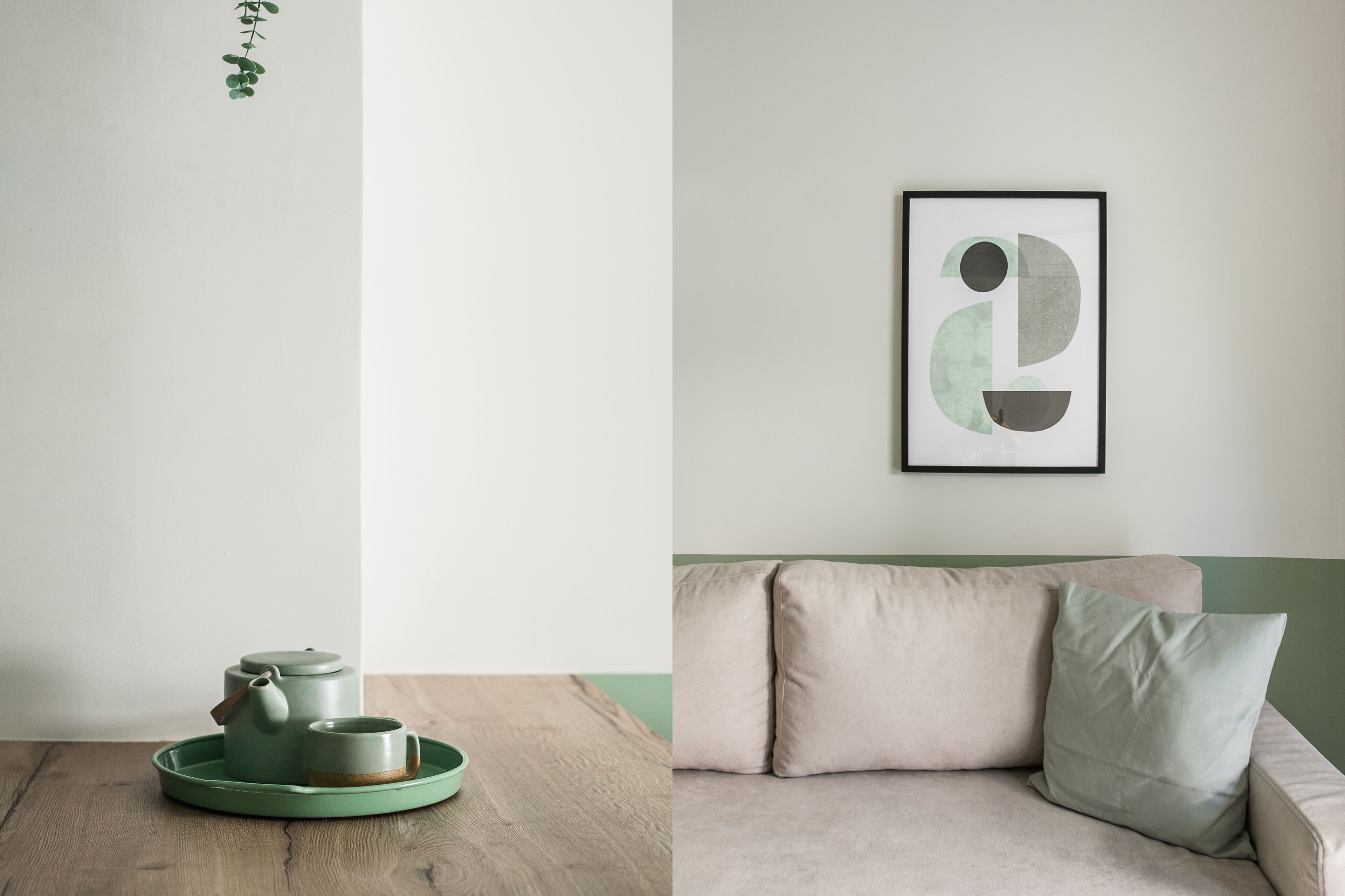 A minimalist room with a wooden table, a green tray with a teapot and cup, a beige sofa, and a framed abstract art piece on the wall.