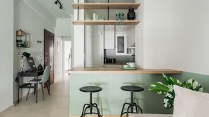 Cozinha moderna com ilha central, banquetas de bar e área de jantar com mesa e cadeira.