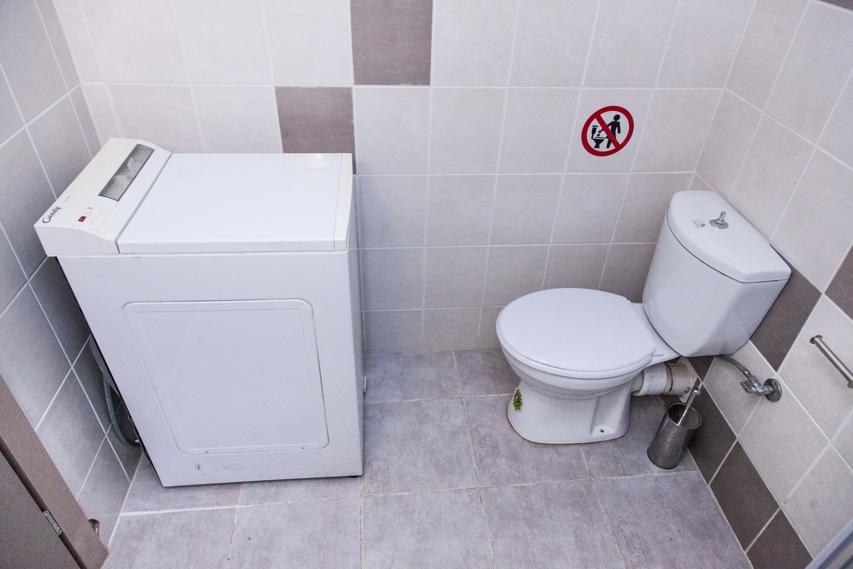 A compact bathroom with a white toilet, a small sink, and a white washing machine.