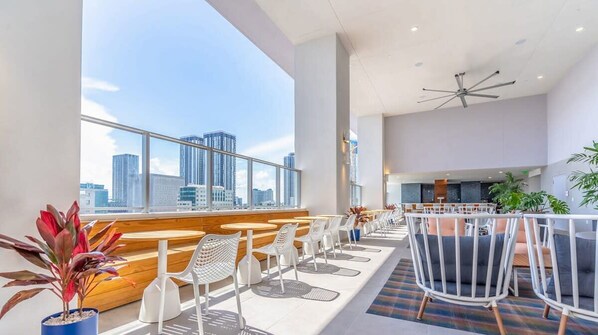 Relax in a spacious room with a city view, featuring cushioned seating areas and a wooden bench.