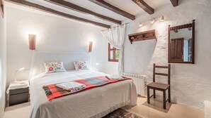 Ein Schlafzimmer mit Bett, Nachttisch, Stuhl, Spiegel und Fenster.