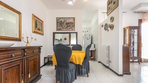 A dining area with a table set for two, a cabinet with drawers, a mirror, and a painting on the wall.