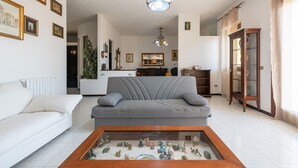 A living room with a grey sofa, a coffee table with figurines, a chandelier, and a wooden cabinet.