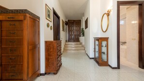 A hallway with a wooden cabinet, a glass cabinet, and a mirror on the wall.