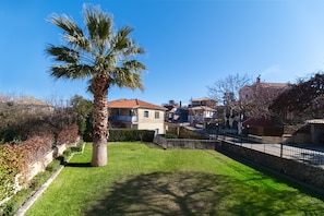 A residential area with a well-maintained lawn, a palm tree, and houses with red-tiled roofs. - Apartment "Villa Votistis A2" with Mountain View, Garden & Wi-Fi (Lefkadas)